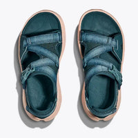 Pair of teal sandals with beige soles on a white background
